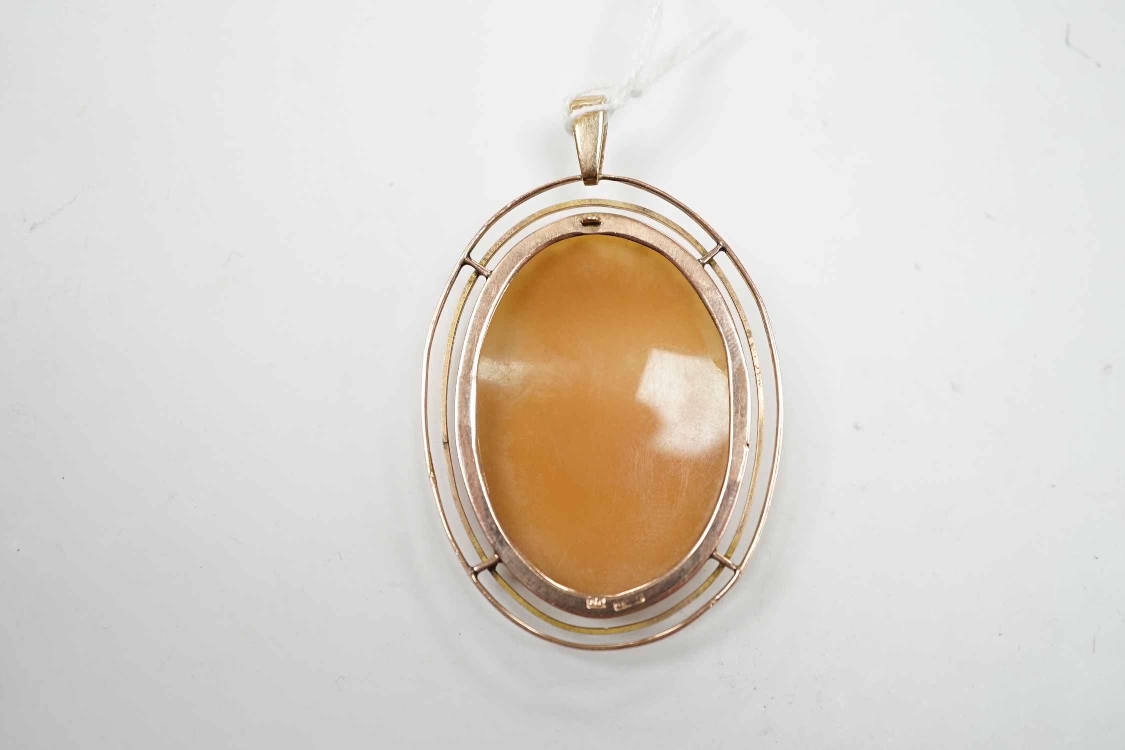 An early 20th century 9ct mounted oval cameo shell pendant, carved with the bust of a lady to sinister, overall 83mm, gross weight 13.2 grams.
